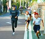 神山小学校児童と併走する県下一周駅伝ランナーら＝南大隅町根占川北