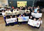 能登に送る黒糖やメッセージを手に笑顔の４年生＝１２日、出水市の下水流小学校