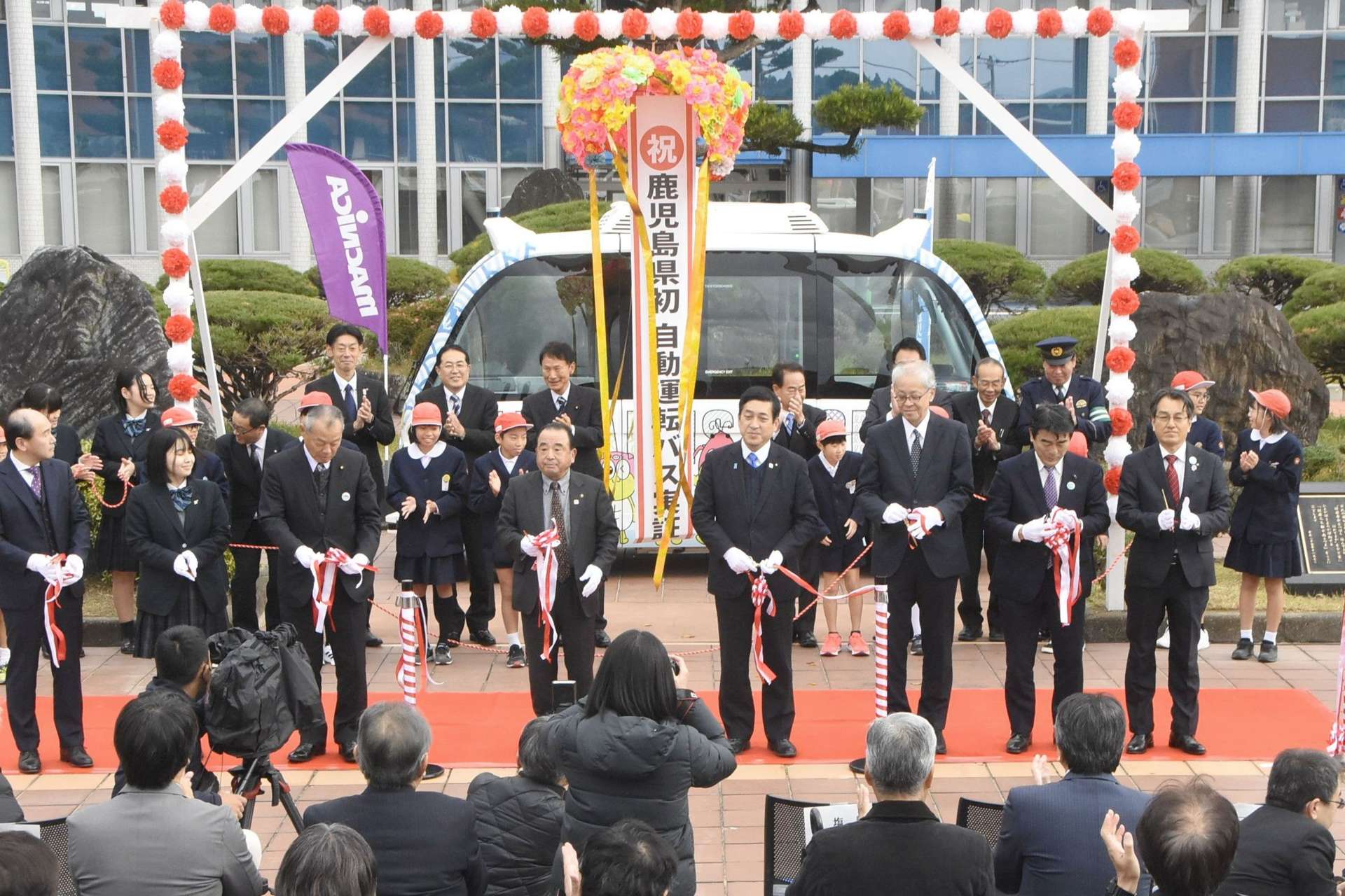 自動運転バスが披露された式典でテープカットする関係者＝１４日午前、南さつま市役所