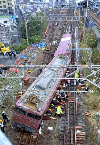 傾いた機関車を水平にする作業員ら＝１５日午前１０時４０分ごろ、薩摩川内市の川内駅
