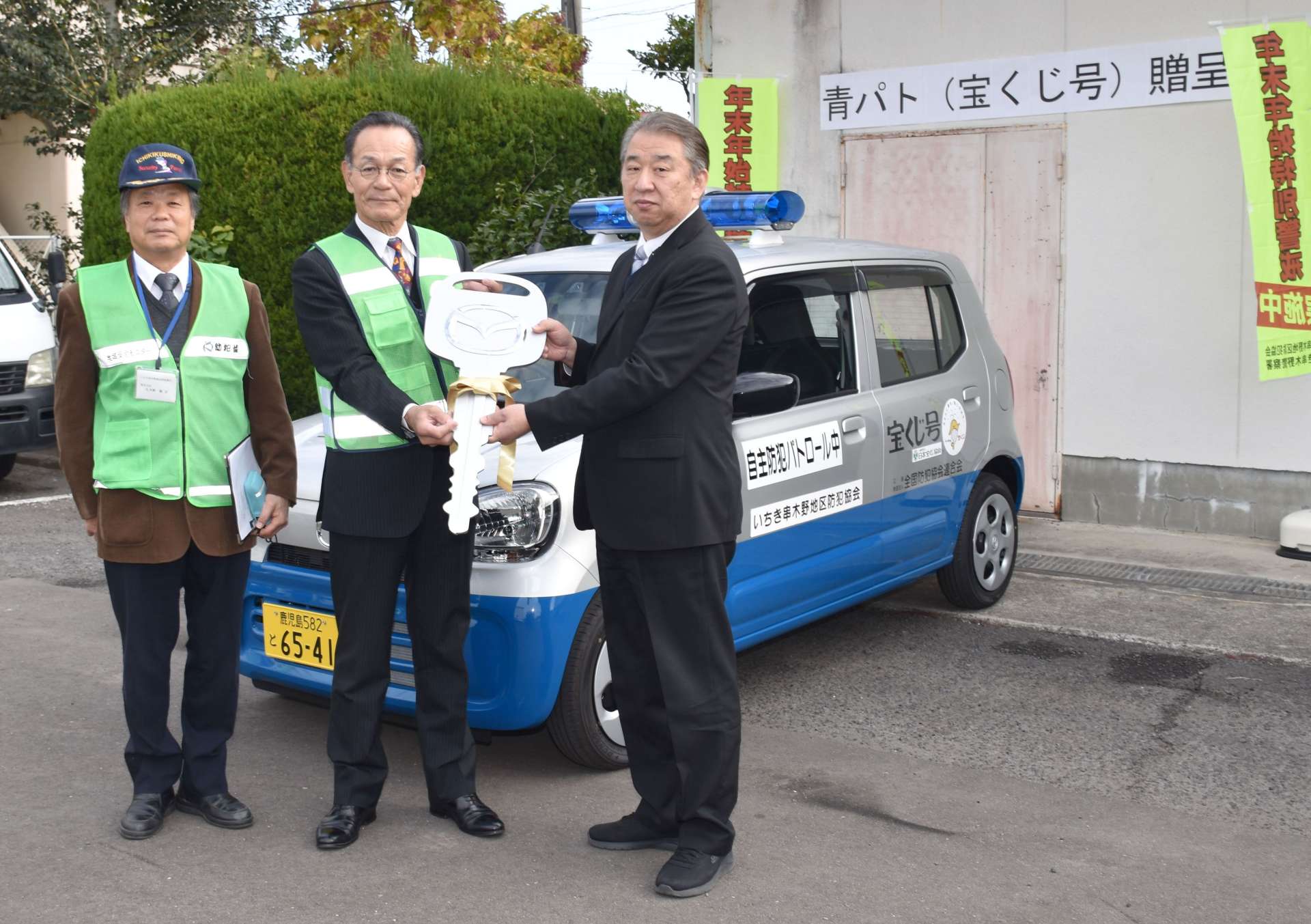 「宝くじ号」のキーのレプリカを受け取るいちき串木野地区防犯協会の中屋謙治会長（中央）ら＝いちき串木野市のいちき串木野警察署