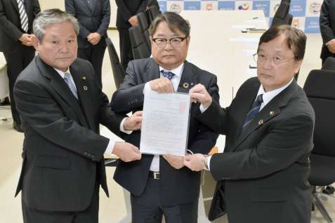 田中良二市長（右）らからの要望書を手にする九州電力の池辺和弘社長（中央）＝１８日、同市役所