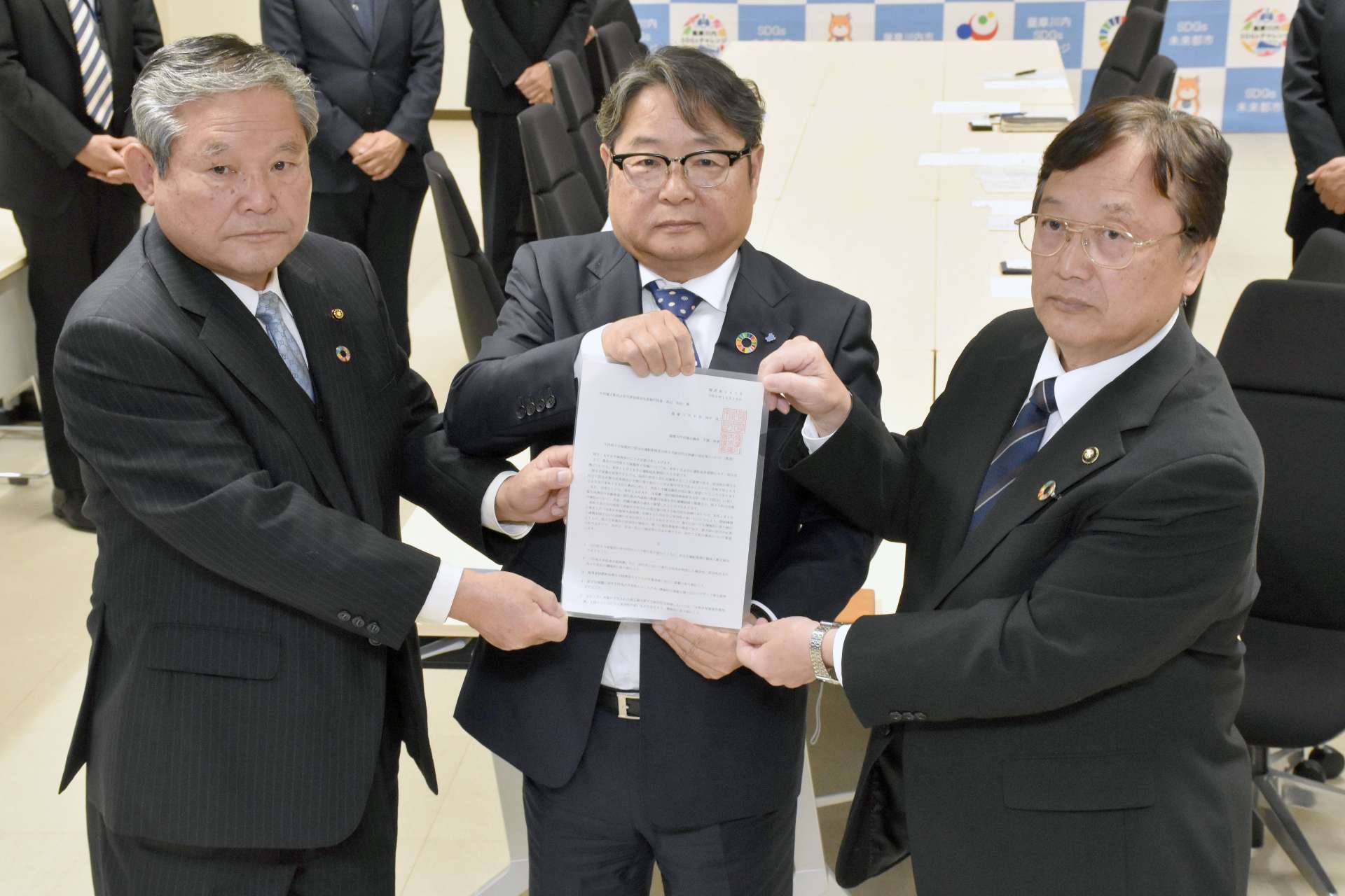 田中良二市長（右）らからの要望書を手にする九州電力の池辺和弘社長（中央）＝１８日、同市役所