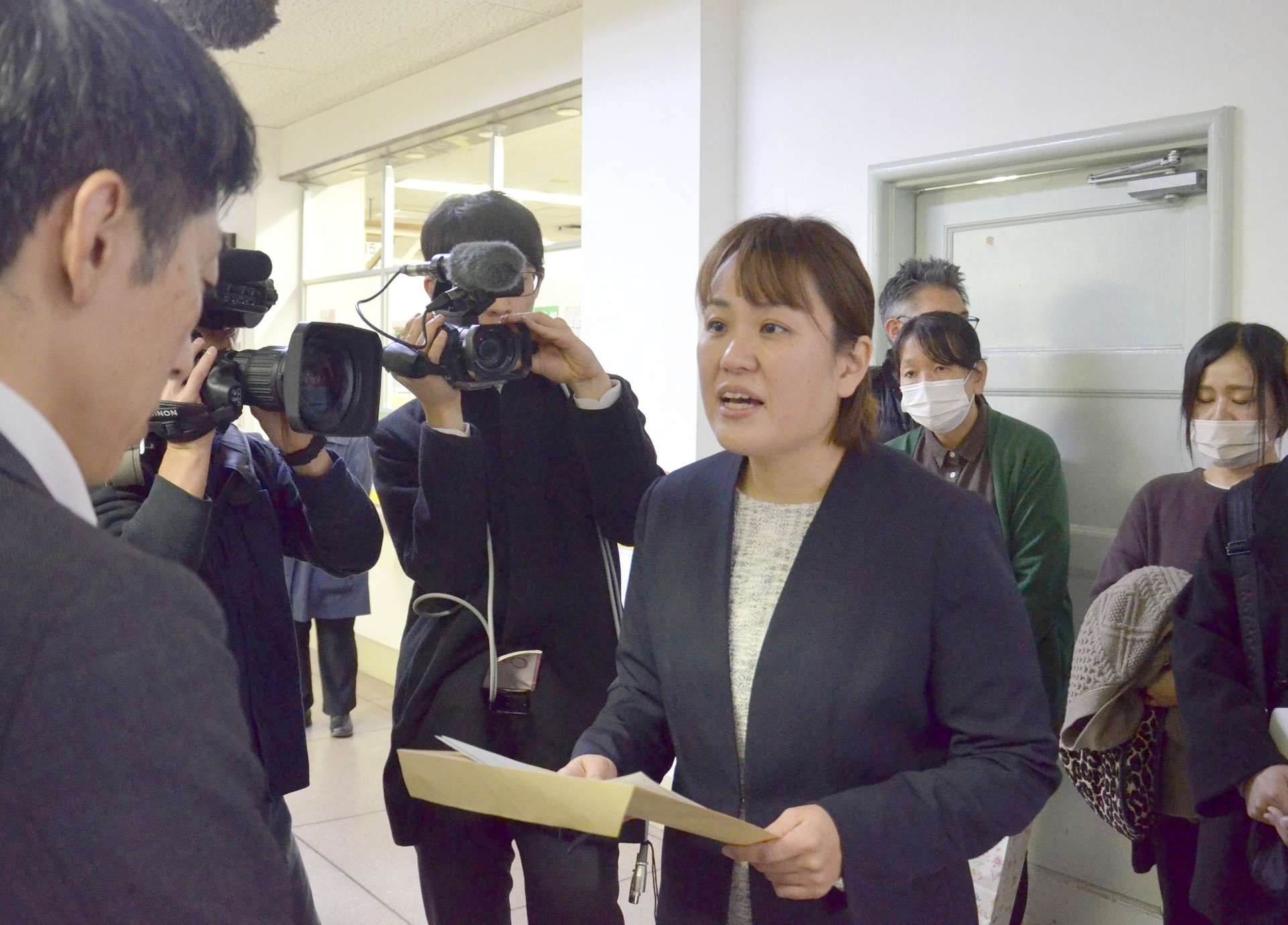 鹿児島市職員に要望書を手渡す鮫島梨紗代表（右）＝１８日、市役所