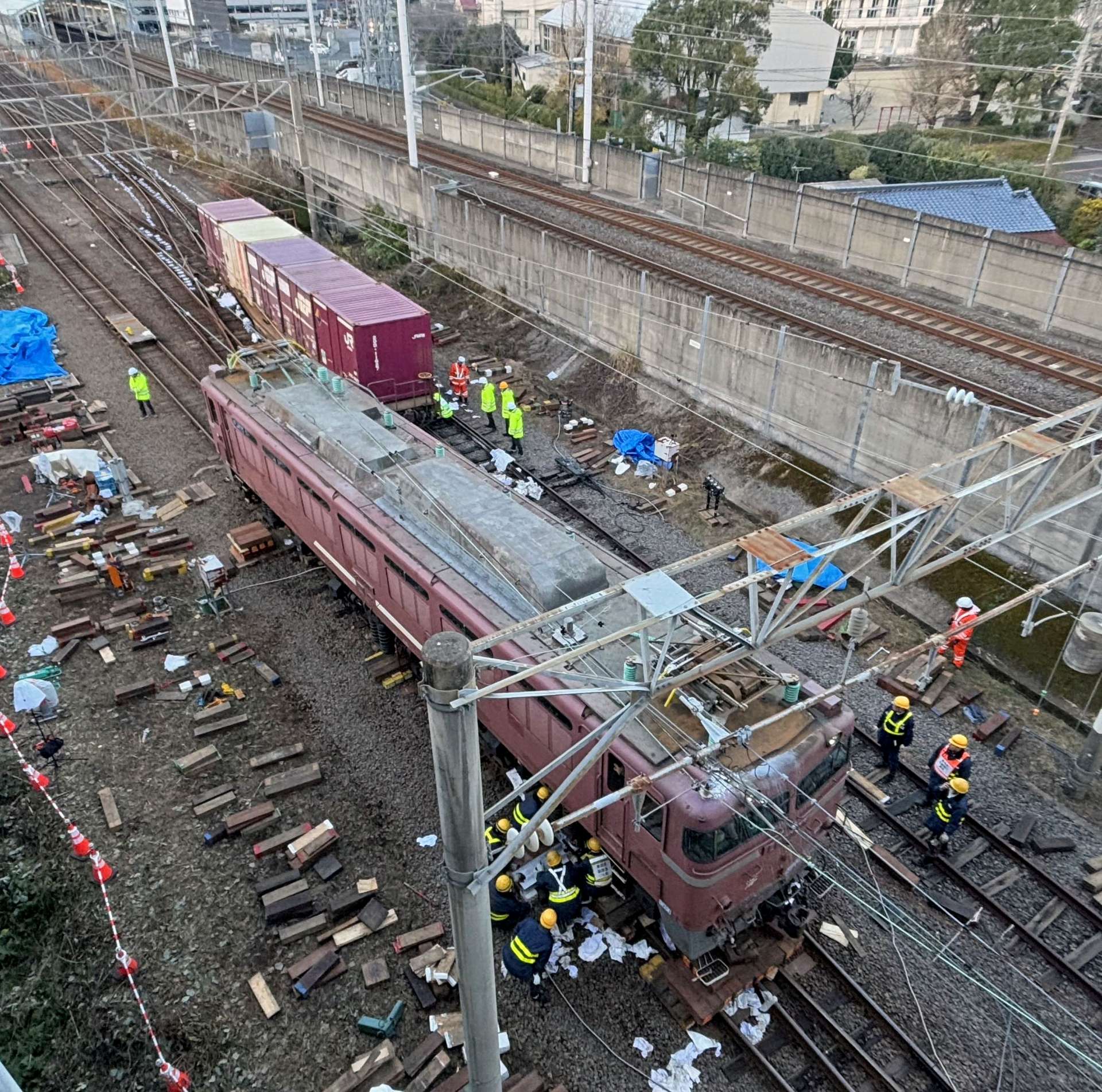 〈別カット〉機関車と貨車の復旧作業に当たる作業員ら＝１８日午後４時５０分ごろ、薩摩川内市