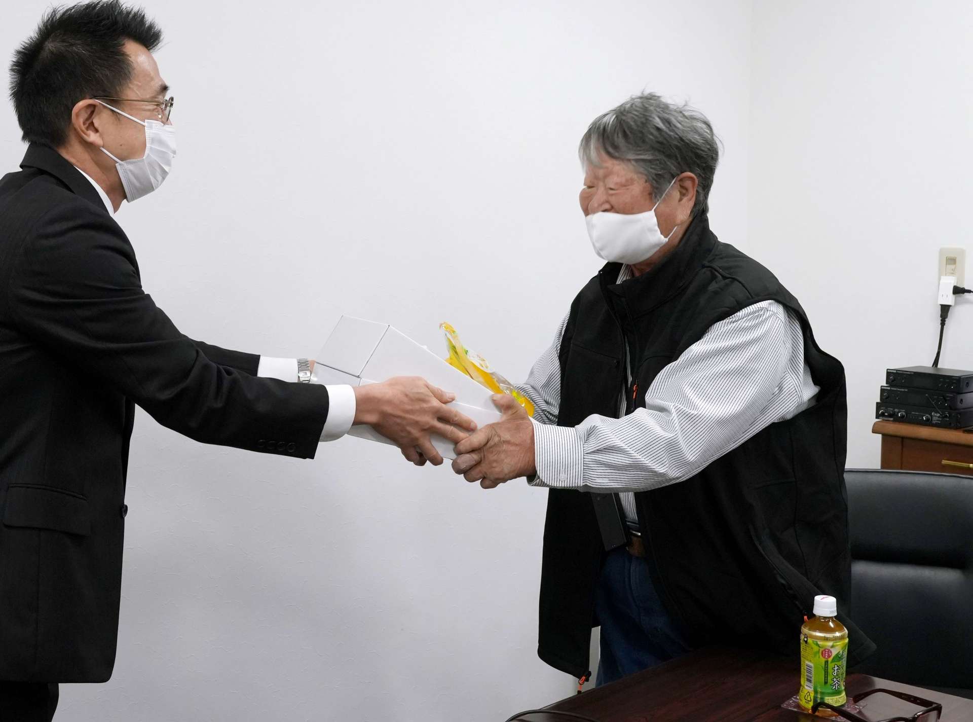 「ふるさとお楽しみ便」を受け取る星塚敬愛園の山口文夫自治会長＝１７日、鹿屋市星塚町