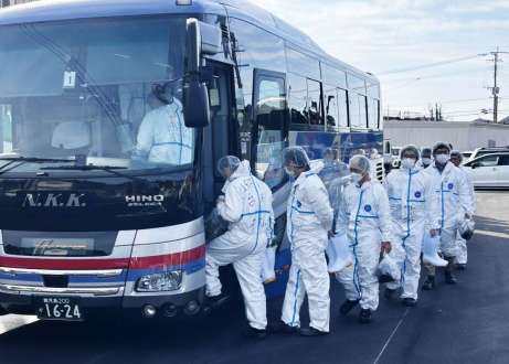 発生農場に向かうため防護服を着てバスに乗り込む鹿児島県職員ら＝２０日午前９時４５分ごろ、霧島市福山