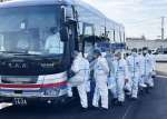 発生農場に向かうため防護服を着てバスに乗り込む鹿児島県職員ら＝２０日午前９時４５分ごろ、霧島市福山