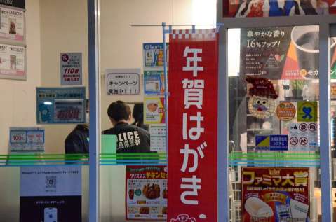 （別カット）強盗現場のコンビニを調べる警察官＝２２日午前７時２０分ごろ、鹿児島市上之園町