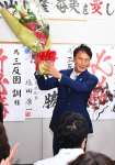 花束を掲げて当選を喜ぶ三反園訓さん＝１０月２７日、鹿児島市谷山中央３丁目