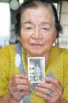 義妹の前之原ミエ子さんの写真を持つ前之原フヂ子さん＝鹿屋市郷之原町