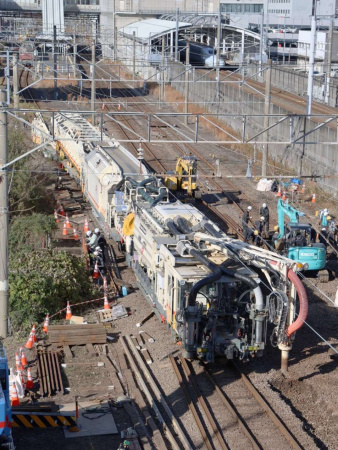 〈別アングル〉道床交換機で砕石を吸い上げる脱線現場。後方右に九州新幹線、左に脱線した機関車が確認できる＝２２日、薩摩川内市の川内駅付近