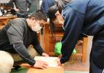 高校生（左）のサポートを受け、板を切る中学生＝出水市の出水中学校