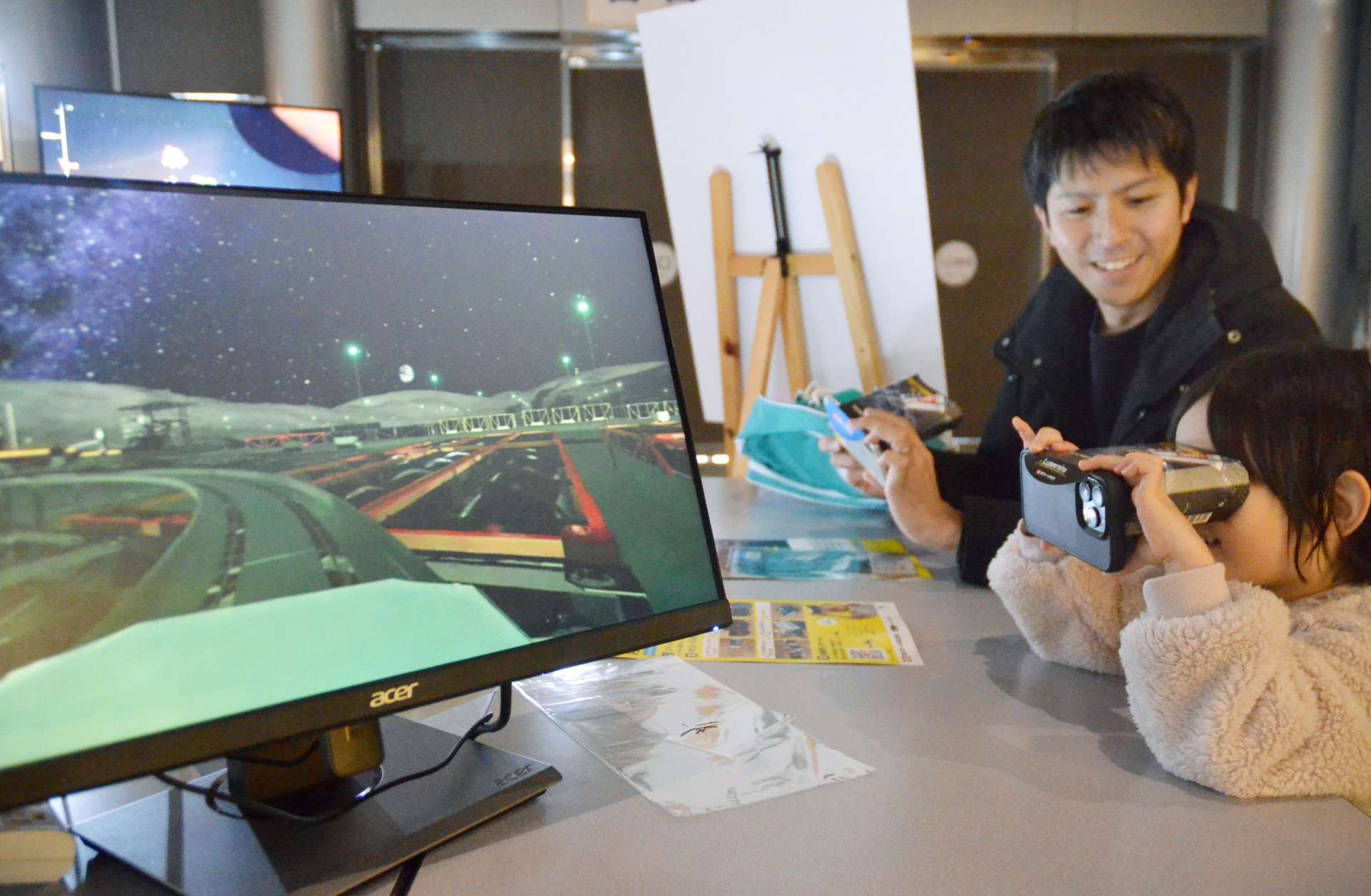月面プラントを仮想現実（ＶＲ）で体験する親子＝鹿児島市立科学館