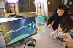 月面プラントを仮想現実（ＶＲ）で体験する親子＝鹿児島市立科学館