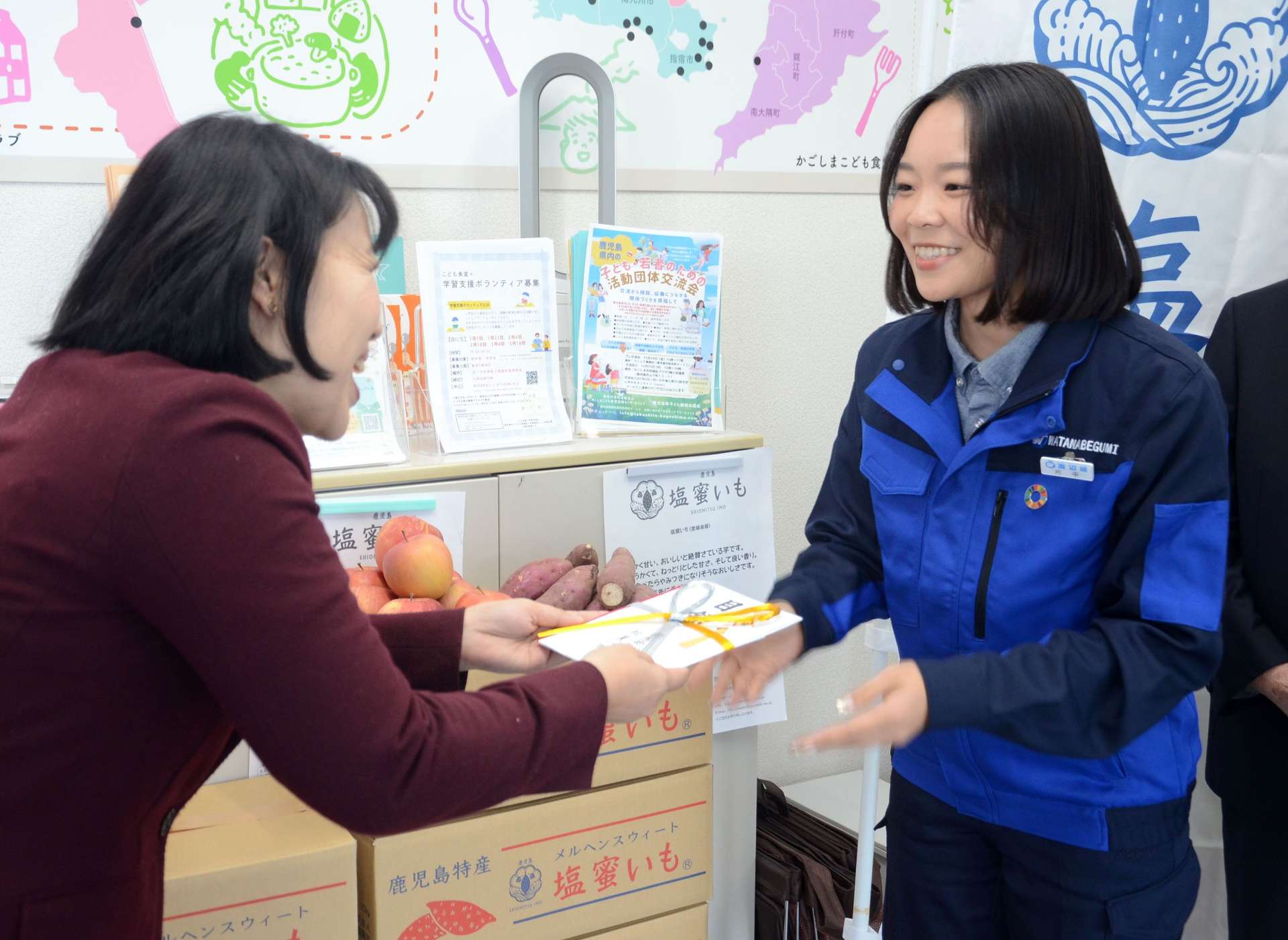 全社員からの寄付を贈る渡辺組の片平千陽さん（右）＝鹿児島市のかごしまこども食堂支援センターたくして