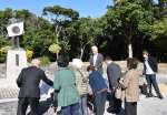 泉芳朗頌徳記念像に献花する参加者＝２５日、伊仙町伊仙の義名山公園