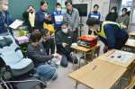 蓄電池とつなぎ、機器の動きを確認する参加者＝２６日、鹿児島市郡元２丁目の中郡小学校