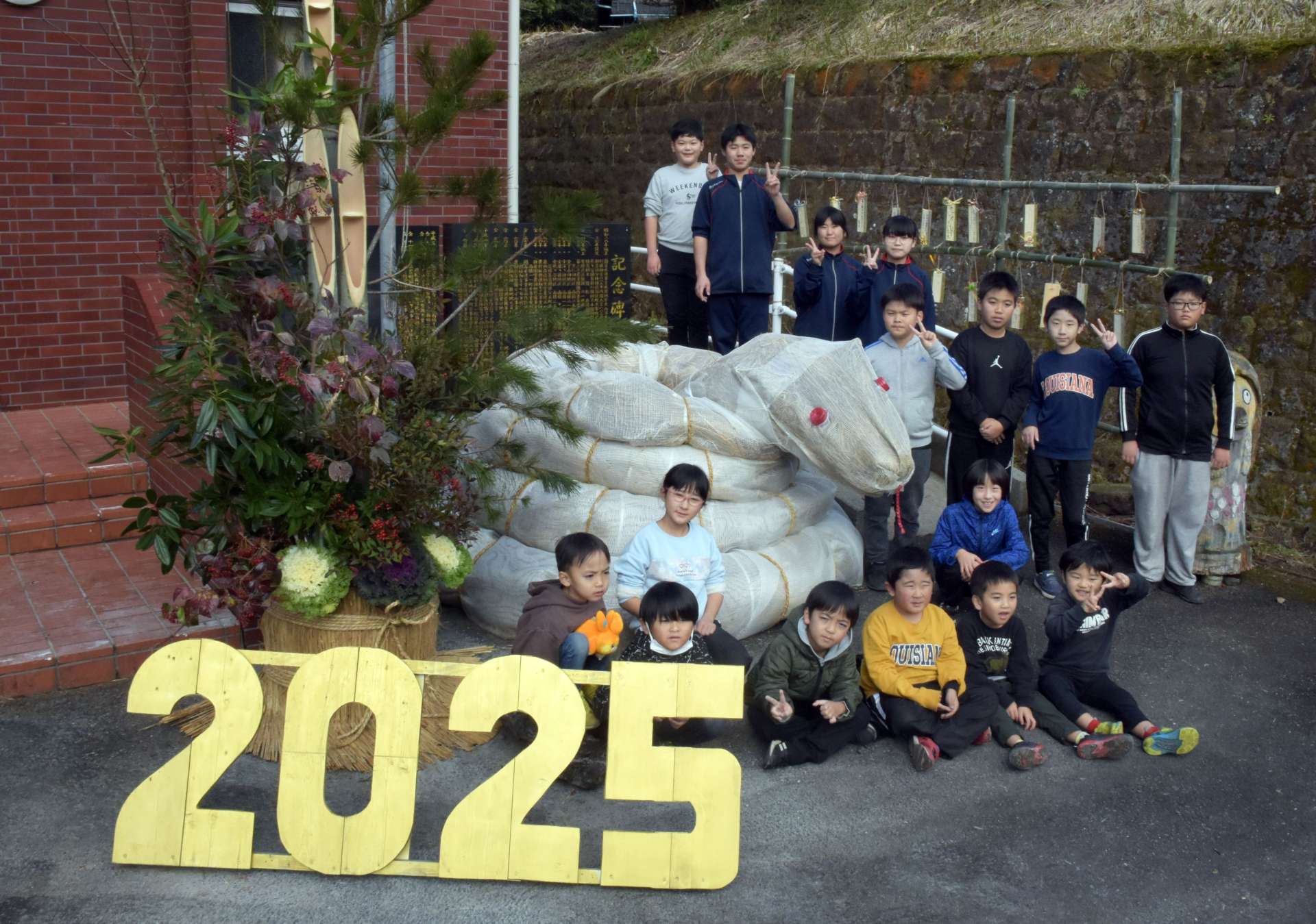 白ヘビの正月飾りの周りで、記念撮影する子どもたち＝南九州市頴娃の谷場営農研修センター