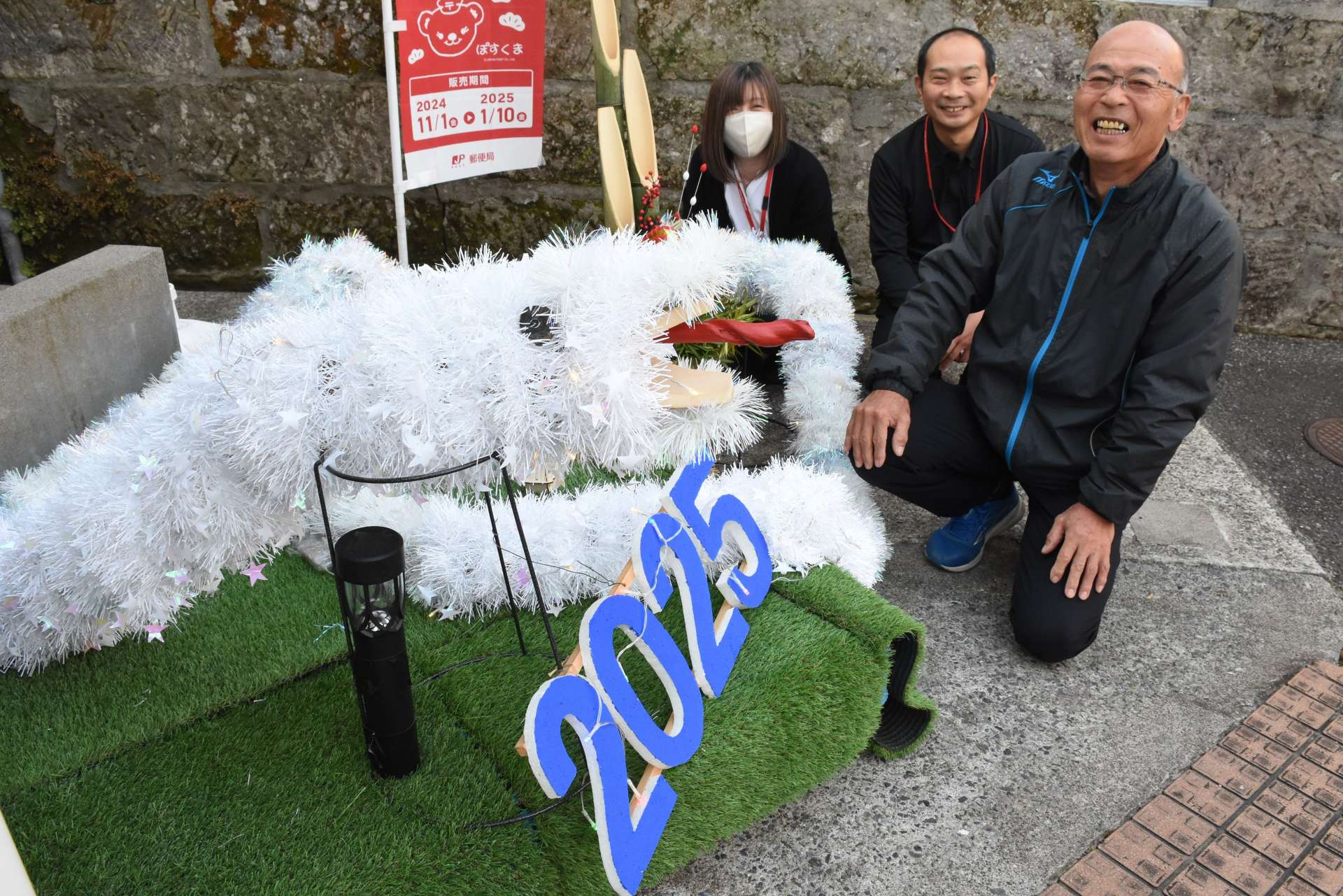 新地寿さん（右）が手作りした白蛇＝志布志市の志布志東町郵便局