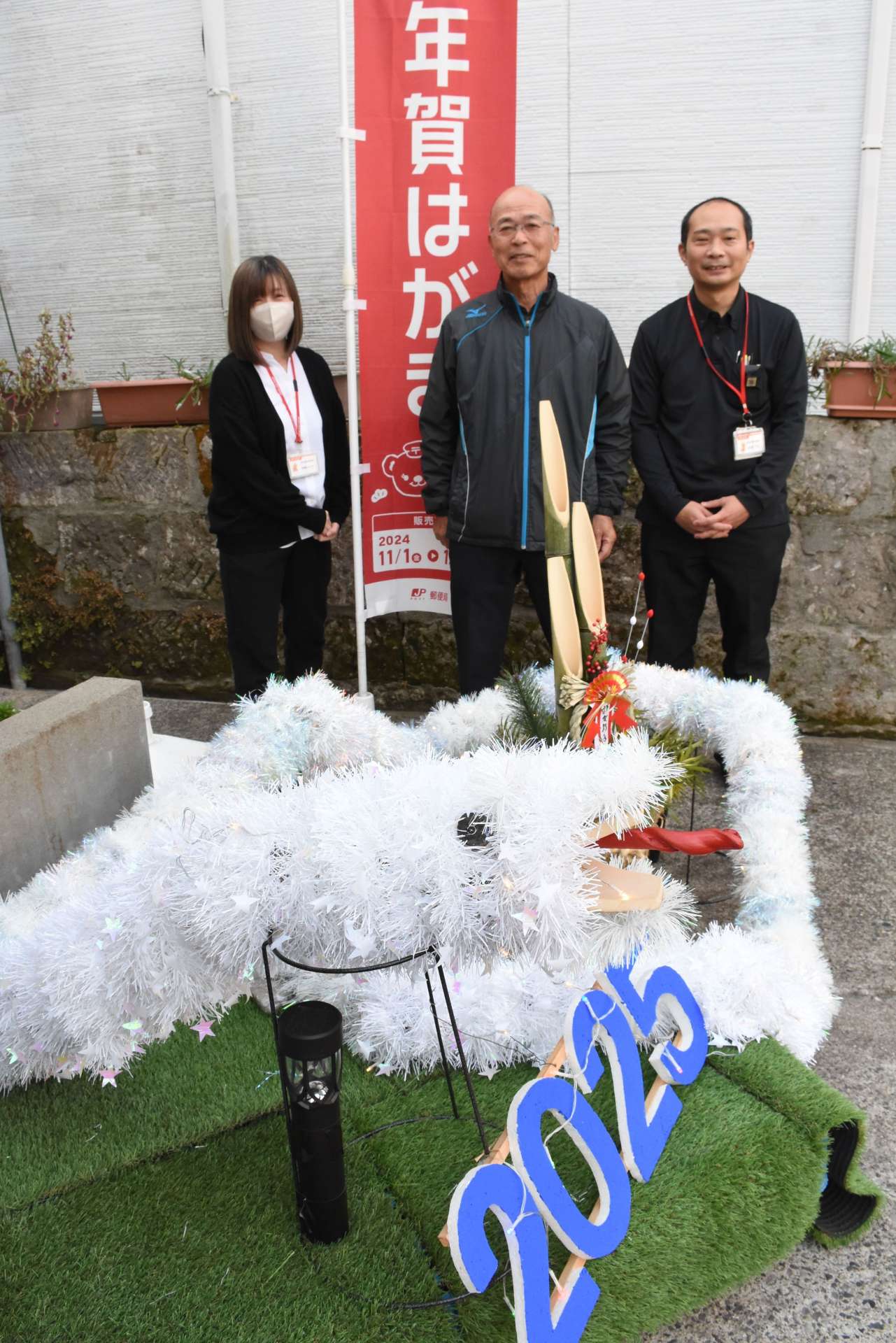 新地寿さん（中央）が手作りした白蛇＝志布志市の志布志東町郵便局