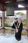 泉福寺の鐘楼につるされた小型の半鐘を、「恒久平和を願ってつく」と語る横井晃仁住職＝さつま町永野