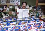 〈関連〉１００冊を超えたスクラップ帳を前に笑顔を見せる緒方槇子さん＝霧島市国分府中町