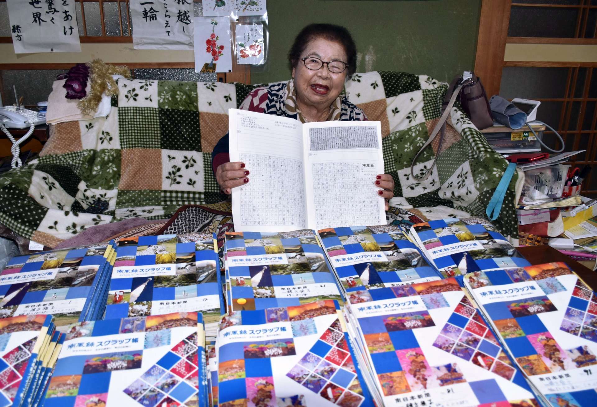 〈関連〉１００冊を超えたスクラップ帳を前に笑顔を見せる緒方槇子さん＝霧島市国分府中町