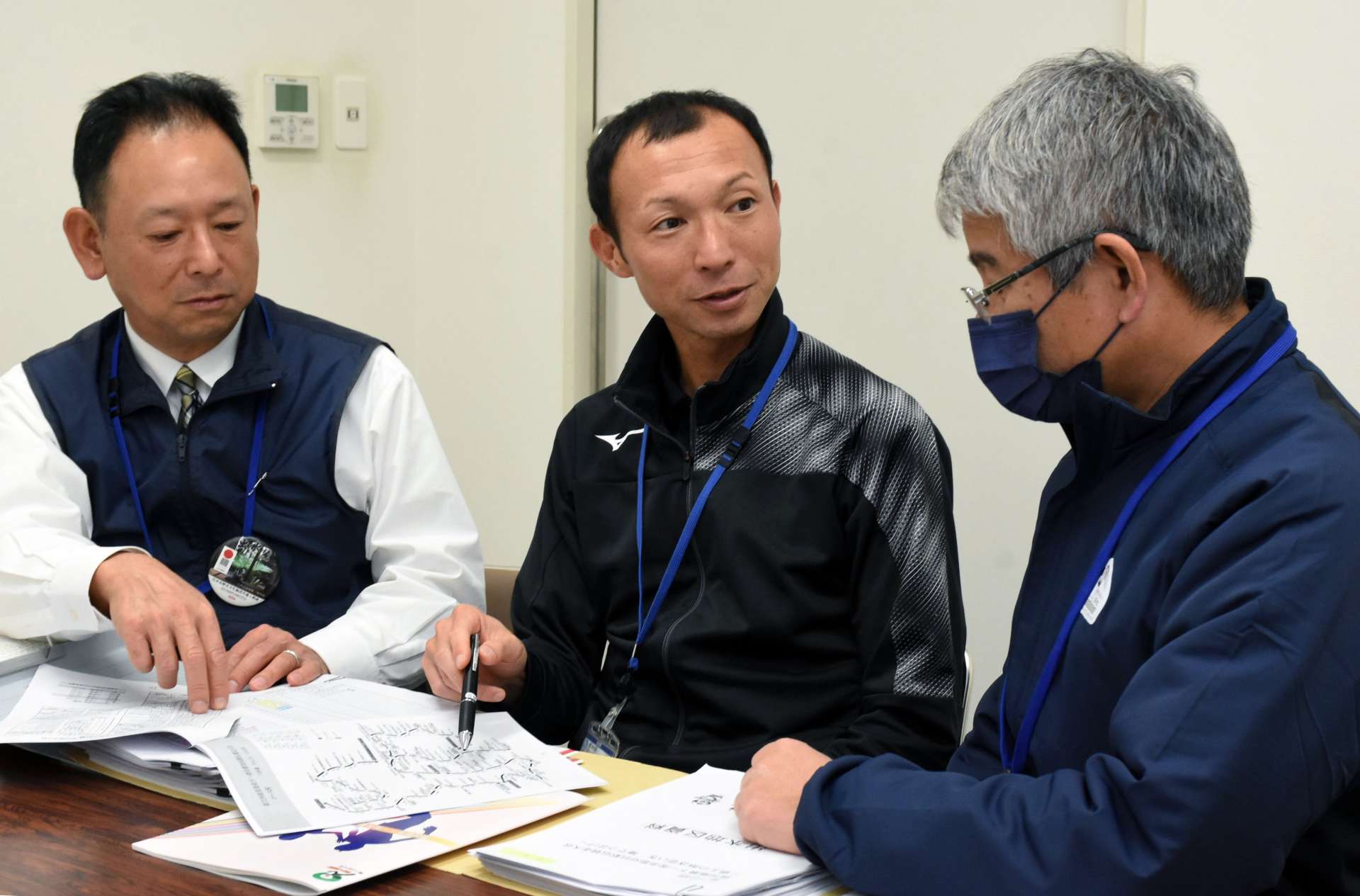 上司と県下一周駅伝の打ち合わせをする吉留達郎さん（中央）＝出水市役所