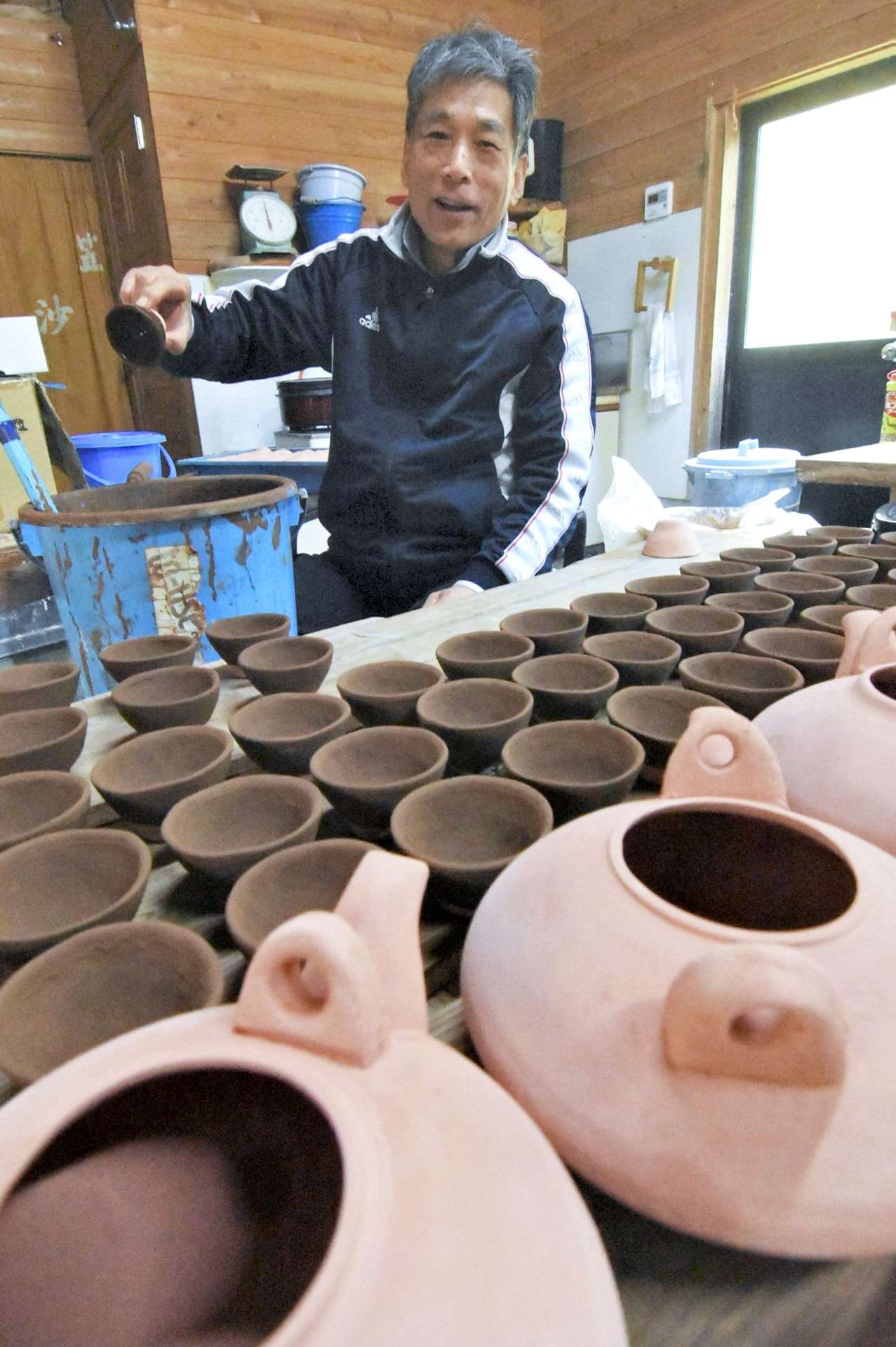 杯や黒ぢょかに釉薬をかけ初窯展へ準備する東祐一さん＝南さつま市の笠沙陶苑