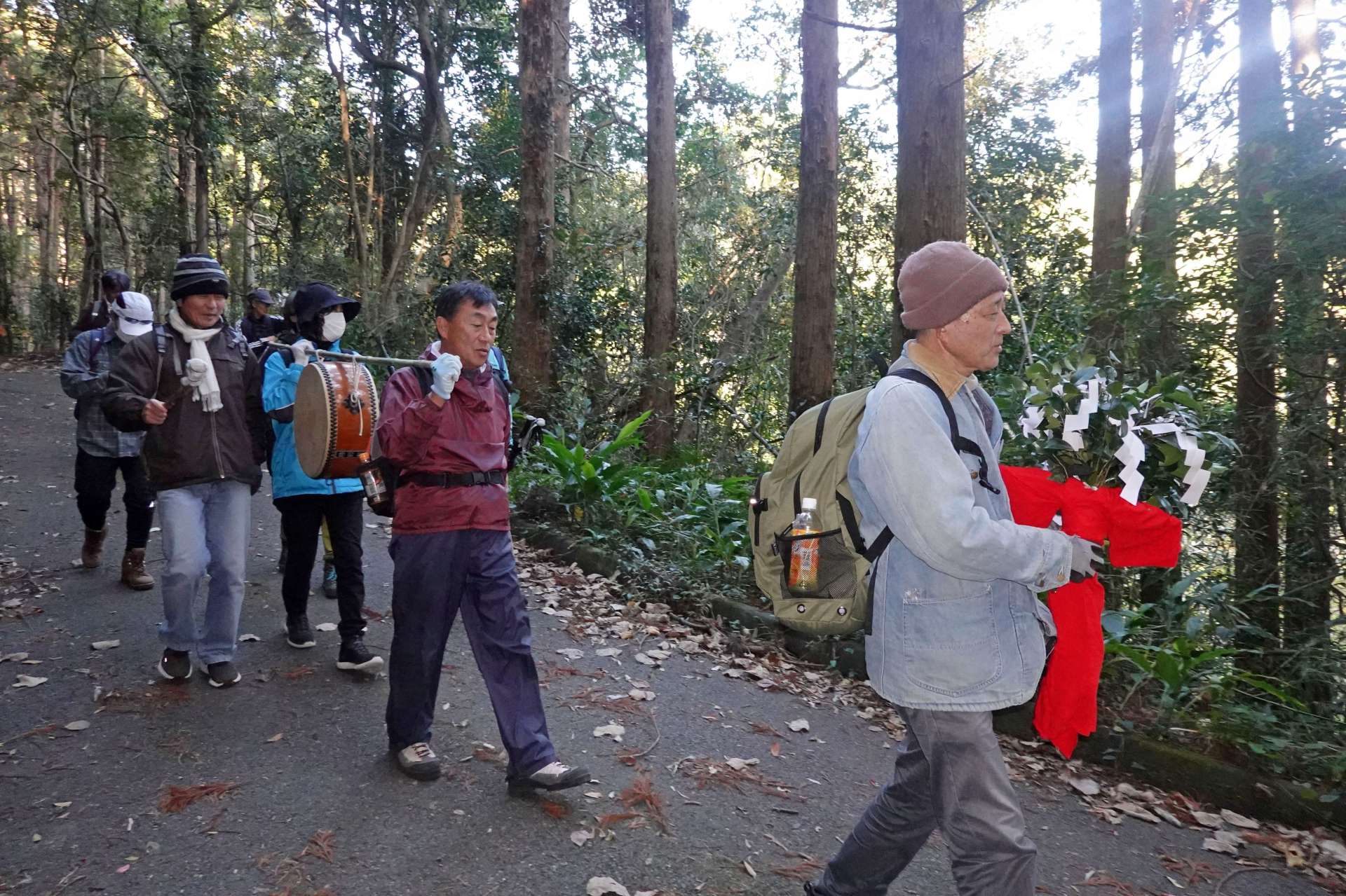 山神が宿る榊の枝の束と共に下山する参加者＝肝付町岸良