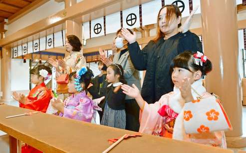 七草祝いの式で手を合わせる晴れ着姿の子どもたち＝７日午前、鹿児島市の照国神社