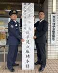 看板を設置する泊義信署長（左）＝８日午前、西之表市の種子島警察署