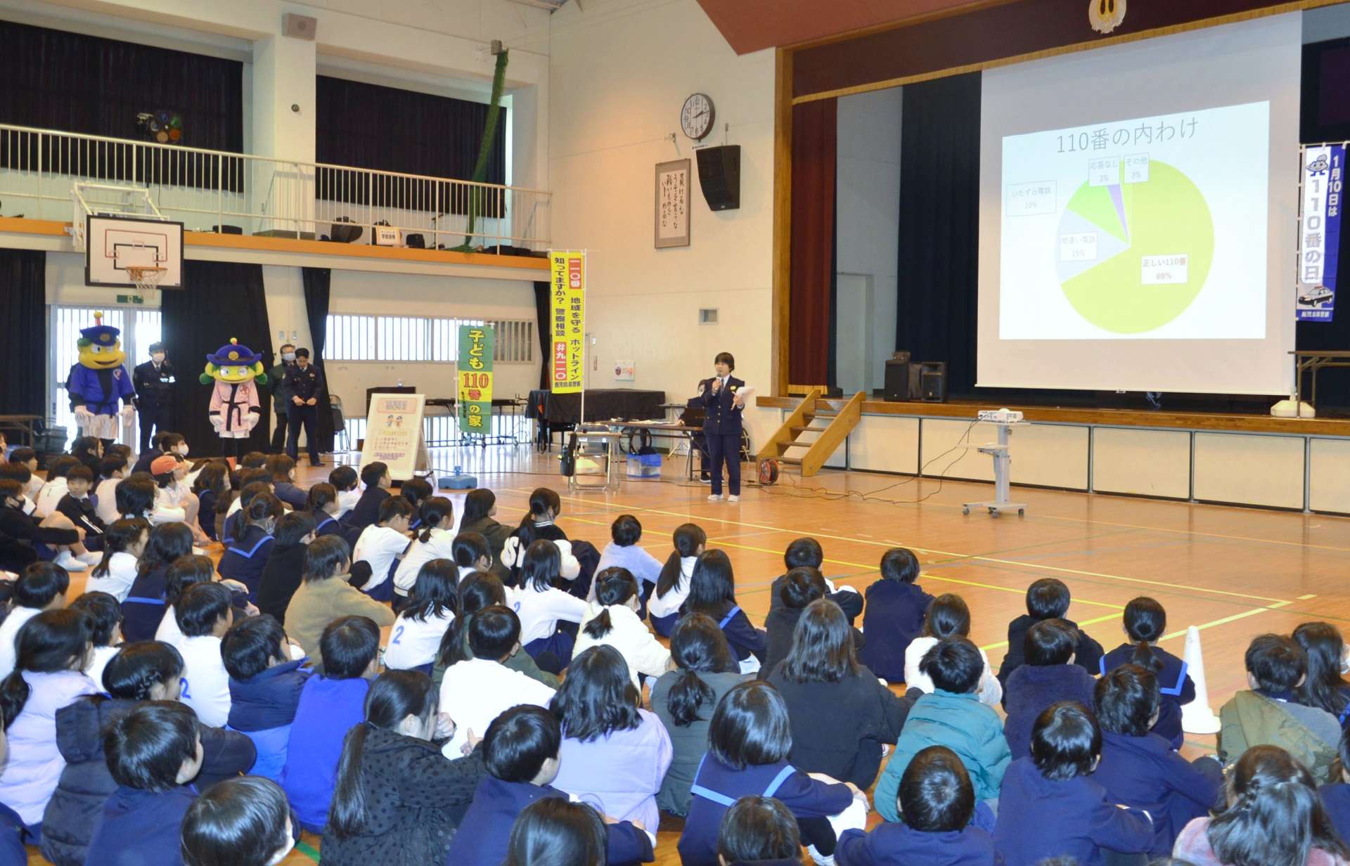 １１０番の正しい使い方を警察官に学ぶ児童＝１０日午後２時１５分ごろ、鹿児島市の山下小学校