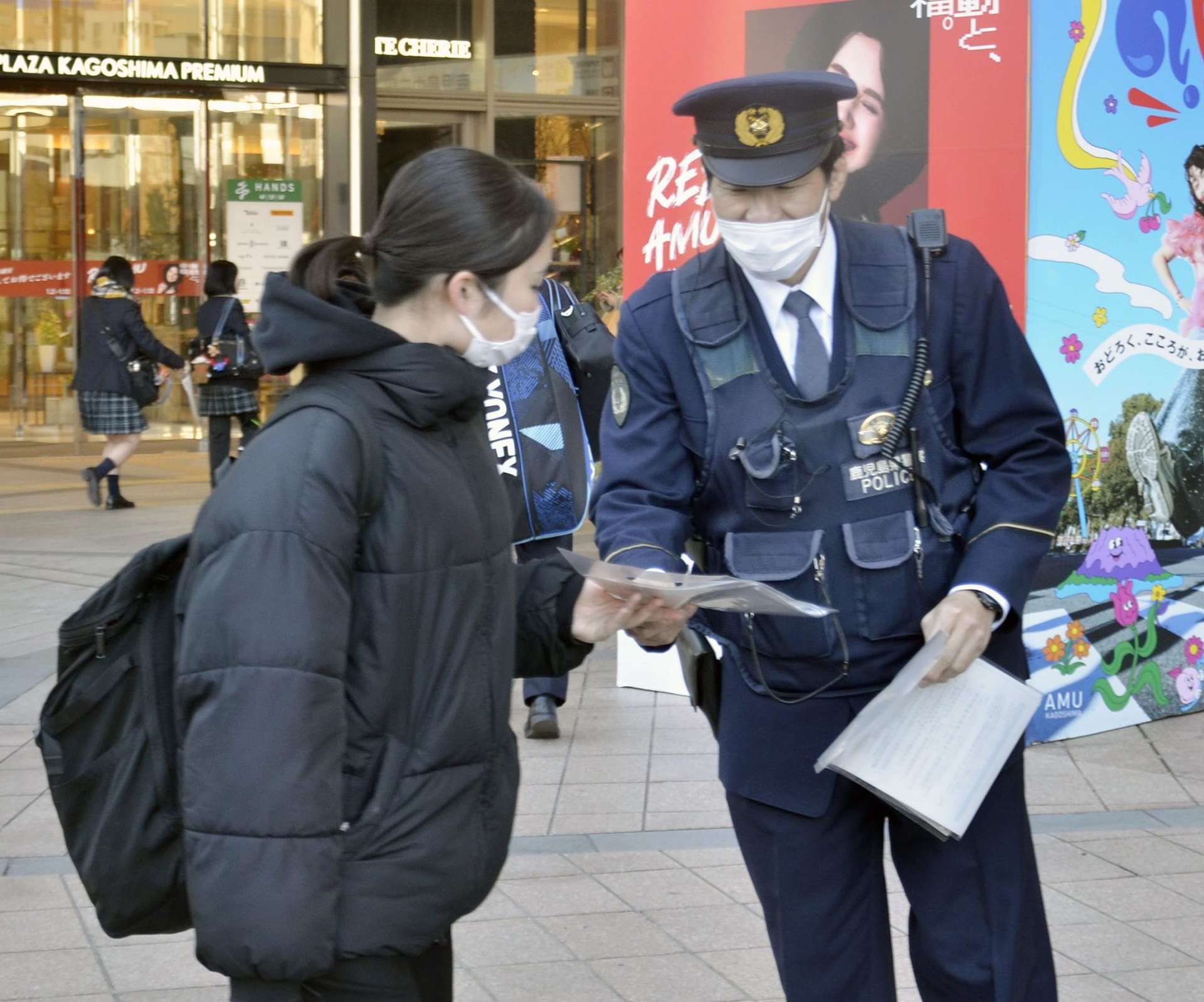 詐欺被害防止へチラシを配る警察官＝１０日午後、鹿児島市の鹿児島中央駅