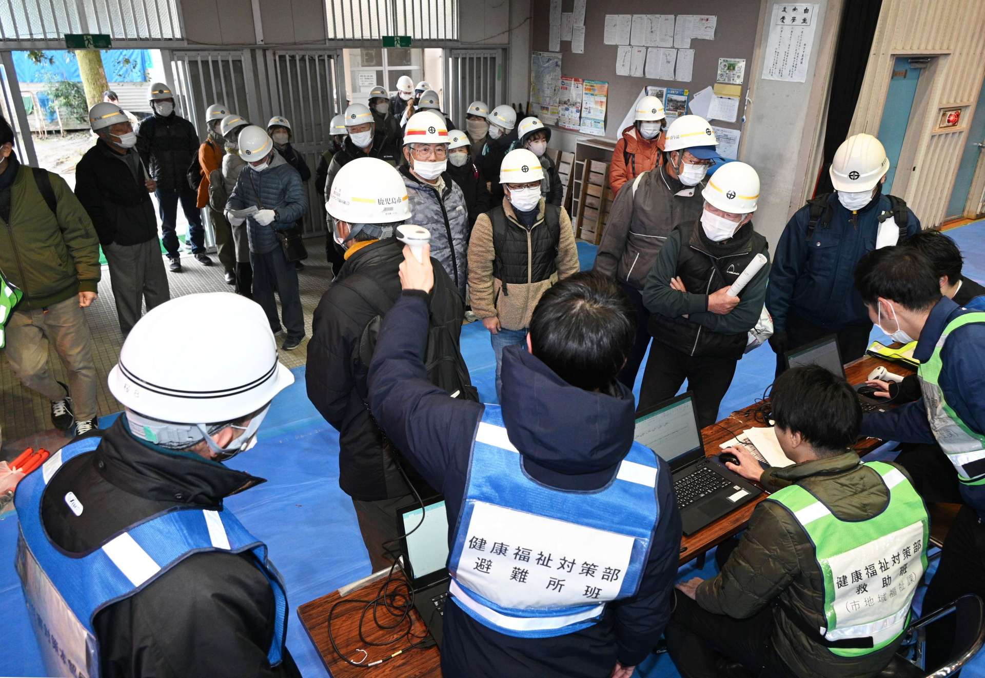ヘルメットのバーコードで、受け付けを済ませる桜島の住民ら＝１１日午前、鹿児島市の谷山中学校