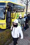 バスを降り、避難所の谷山中学校へ向かう桜島の住民ら＝１１日午前、鹿児島市谷山中央８丁目