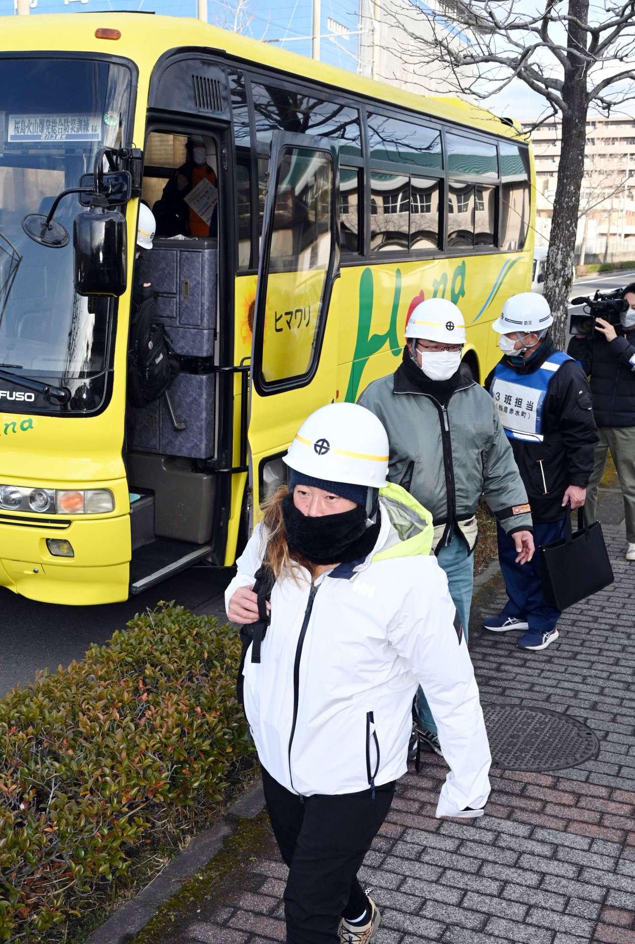 バスを降り、避難所の谷山中学校へ向かう桜島の住民ら＝１１日午前、鹿児島市谷山中央８丁目