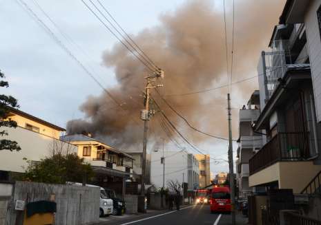 燃える住家から上がる煙＝１１日午後４時５５分、鹿児島市の上荒田町