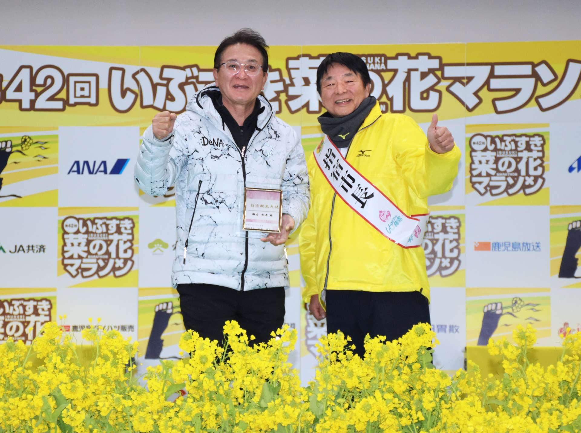 指宿観光大使の委嘱盾を手に、意気込む瀬古利彦さん（左）＝１２日、指宿総合体育館