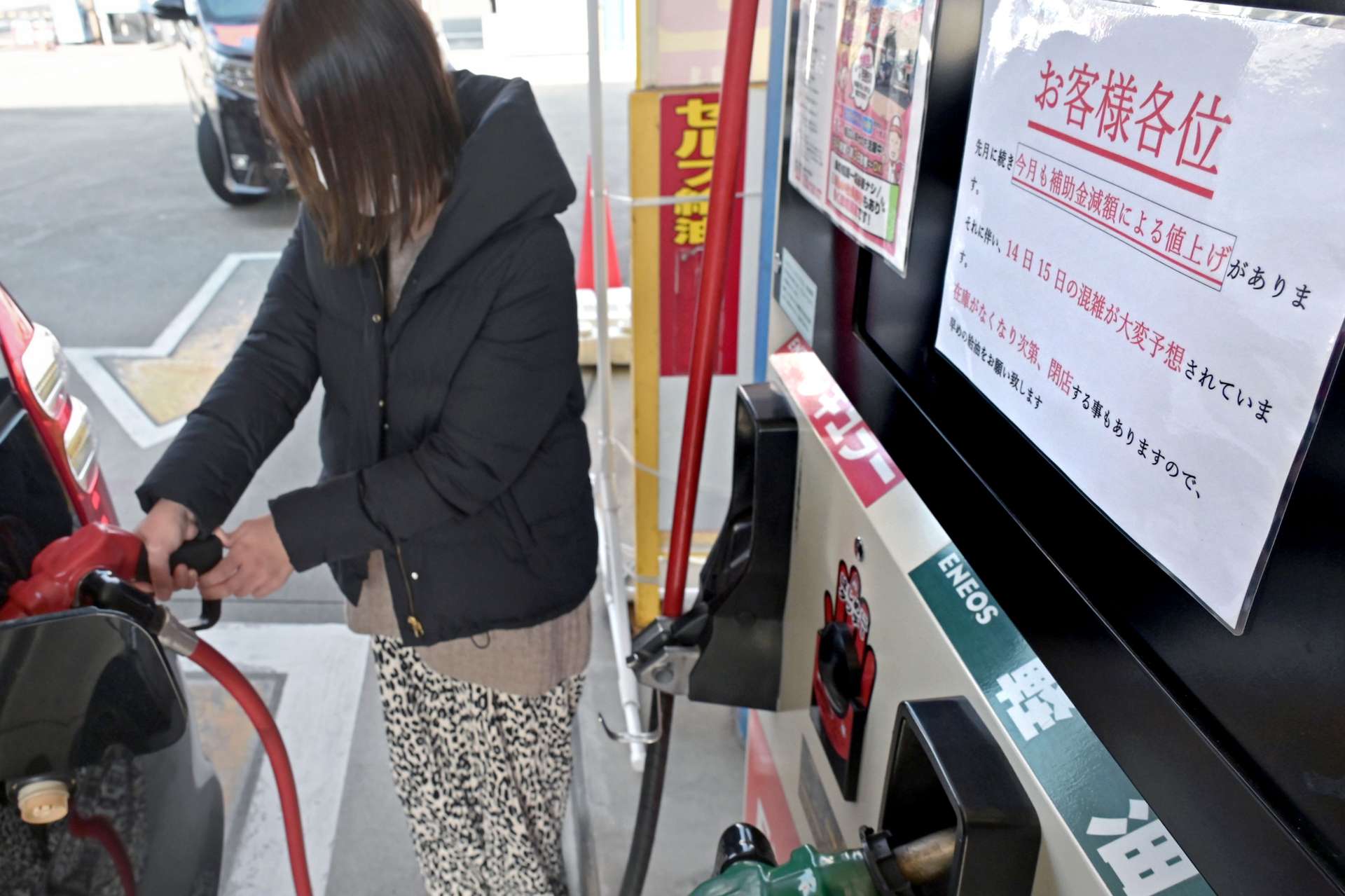 値上げを前にガソリンを給油する女性客＝１４日、鹿児島市のセルフステーション南林寺