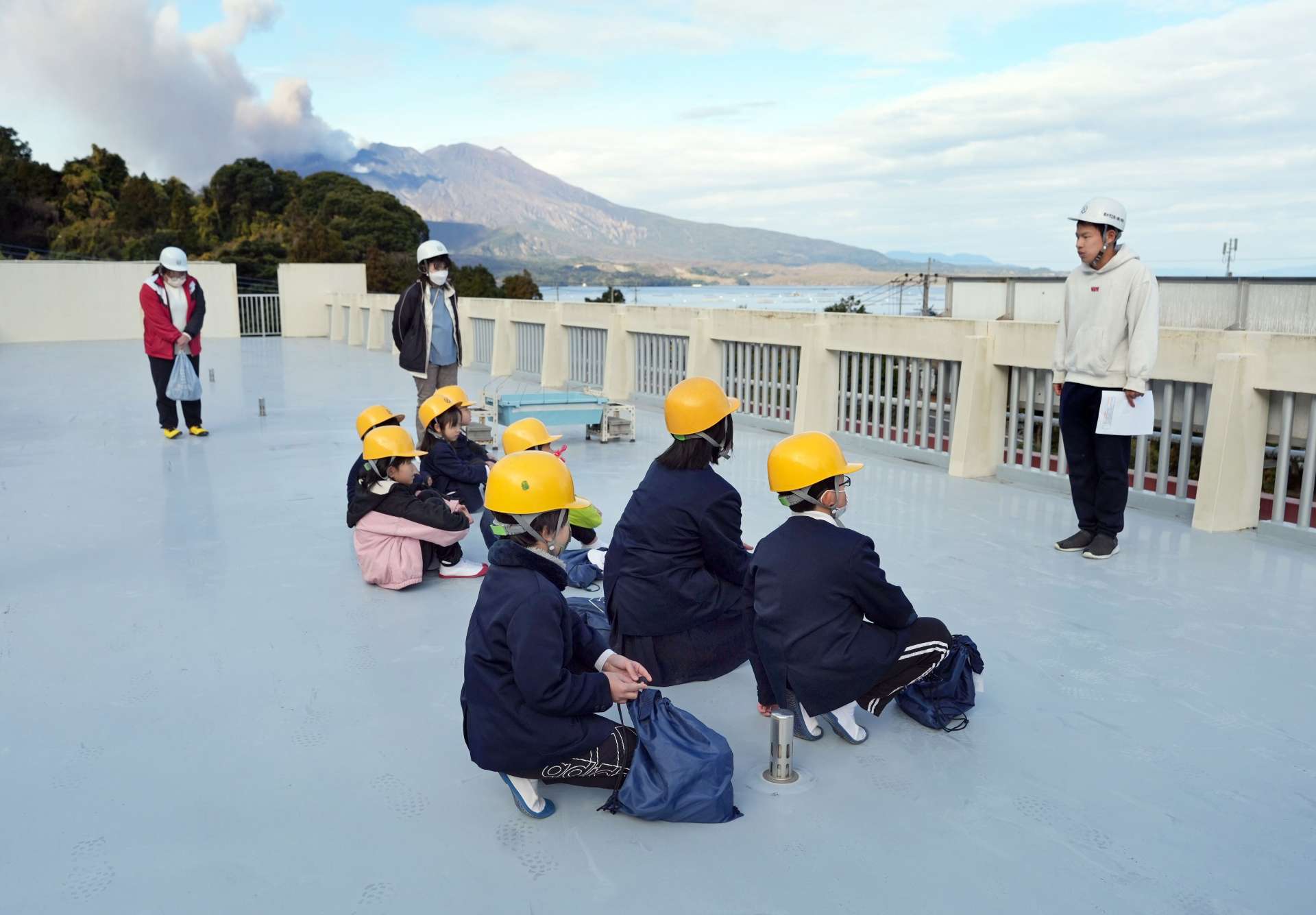 ヘルメットをかぶって屋上に避難する児童＝垂水市の松ケ崎小学校
