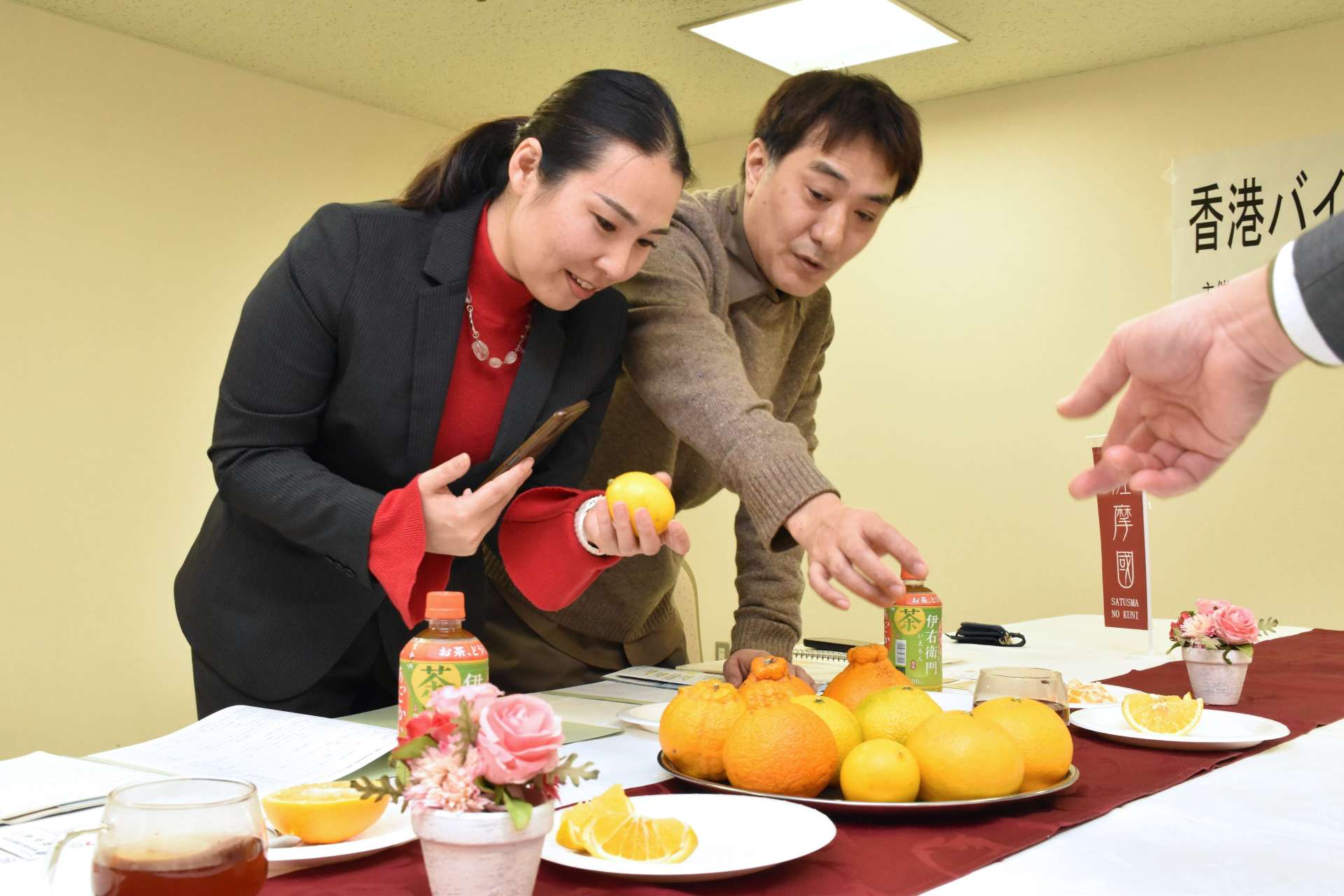 阿久根市で生産するかんきつ類を手にする香港のバイヤーら＝１４日、薩摩川内市のホテルグリーンヒル