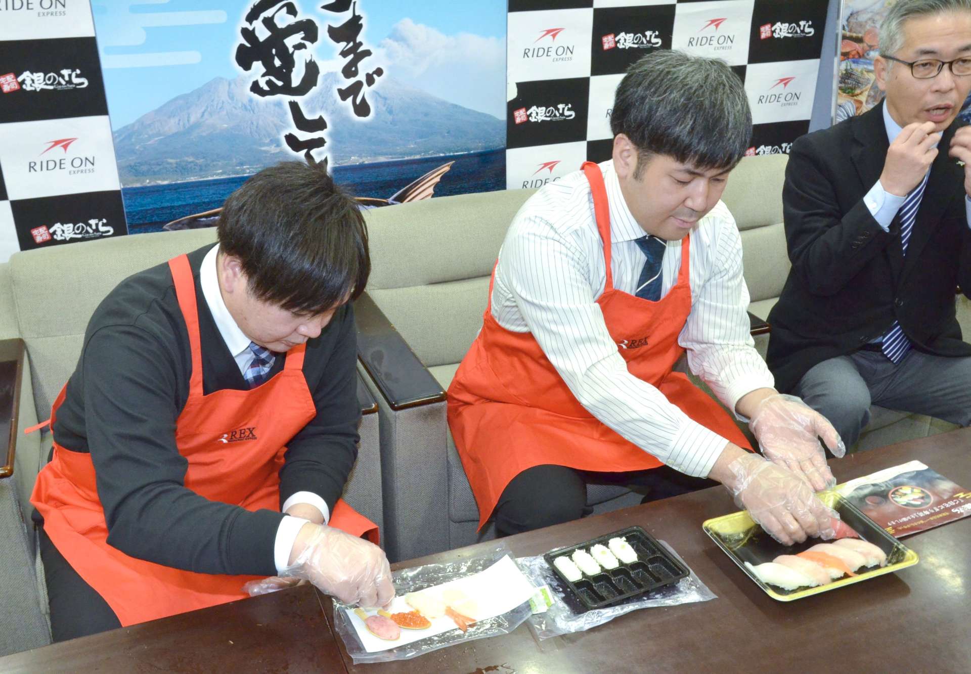 すし握りを実演するライドオンエクスプレスの社員ら＝１５日、県庁