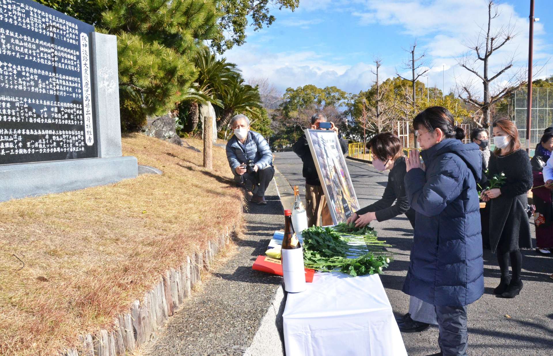 阪神大震災の犠牲者を悼み献花する鹿児島県人会の会員ら＝１７日、神戸市中央区の大倉山公園