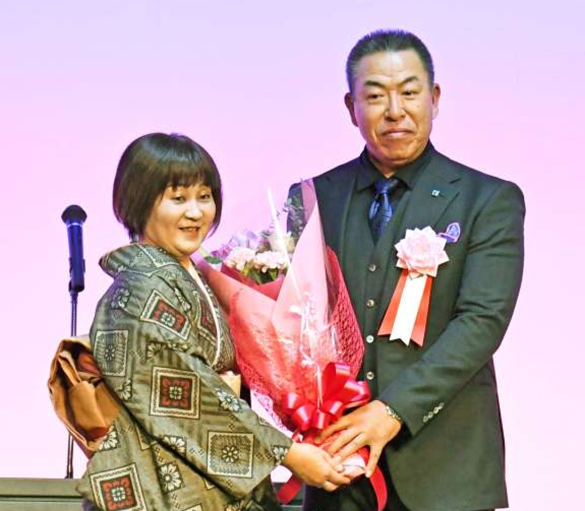 激励会で花束を受け取る井上一樹監督（右）＝１８日、鹿児島市のサンロイヤルホテル