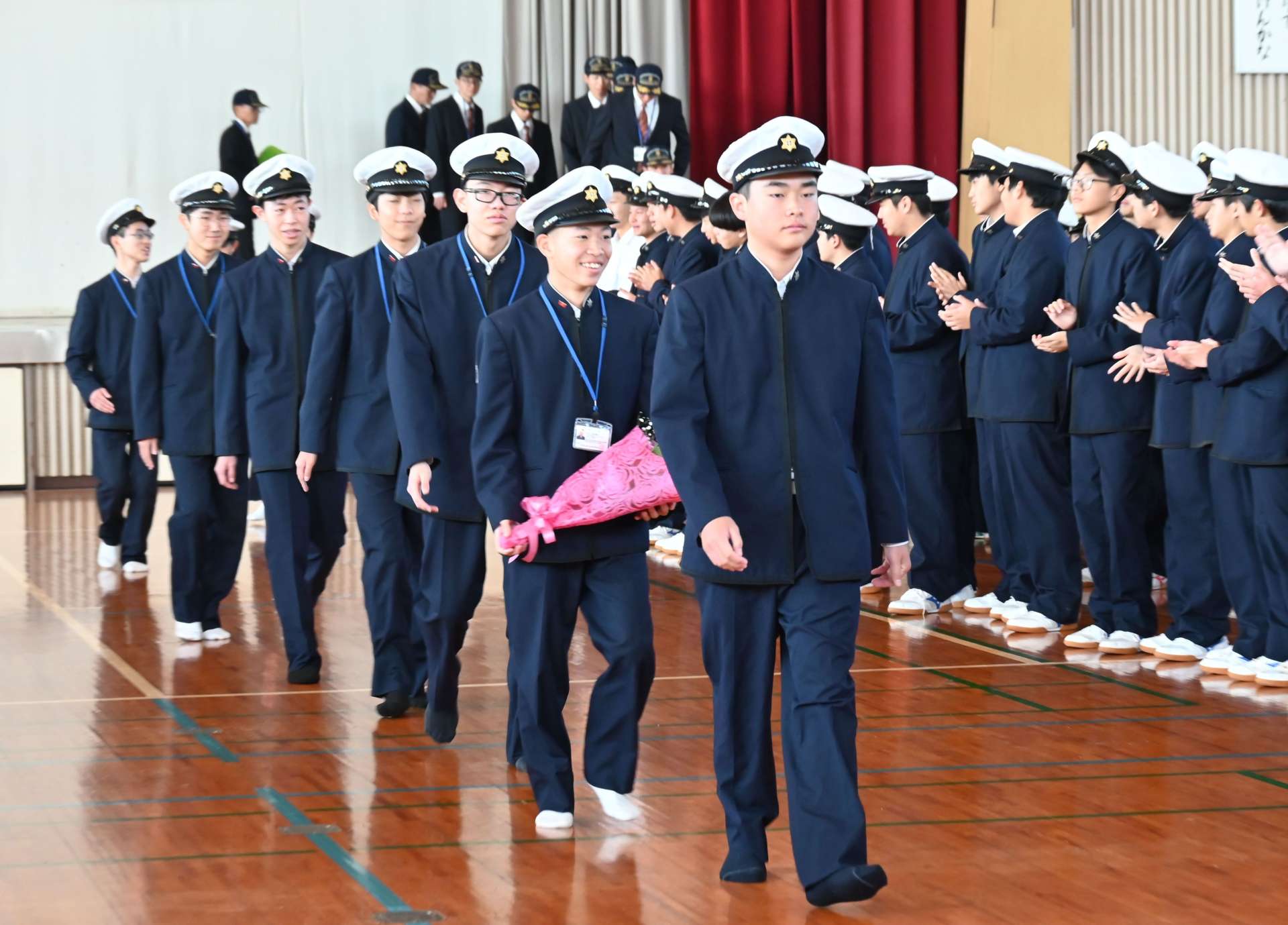 在校生に拍手で見送りを受ける実習生＝１７日、枕崎市の鹿児島水産高校
