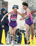 第６中継所、鹿児島の成田（西紫原中、右）から７区玉目（順大）にたすきが渡る＝広島市西区