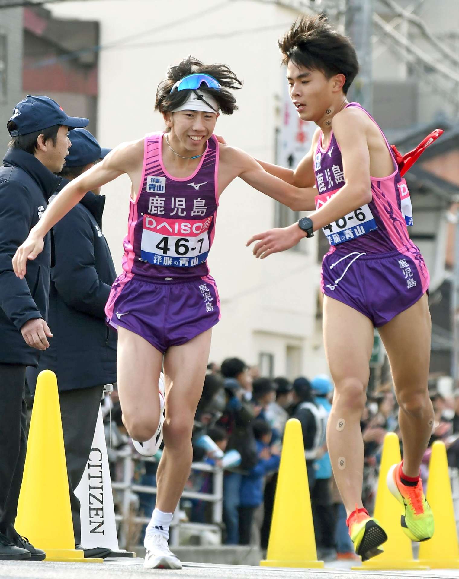 第６中継所、鹿児島の成田（西紫原中、右）から７区玉目（順大）にたすきが渡る＝広島市西区