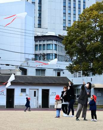 ぽかぽか陽気の中、公園でたこ揚げを楽しむ子どもたち＝２０日午後、鹿児島市中央町